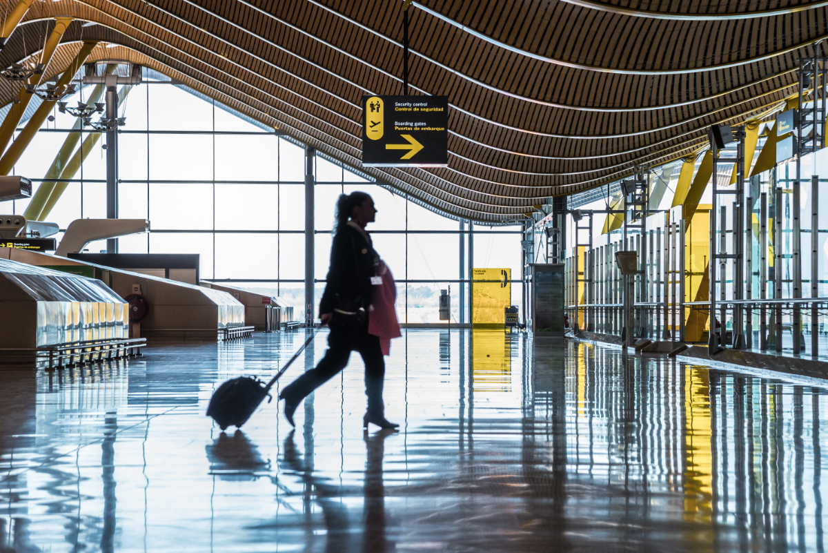 Silhouette de voyageuse avec valise dans un terminal d'aéroport baigné de lumière