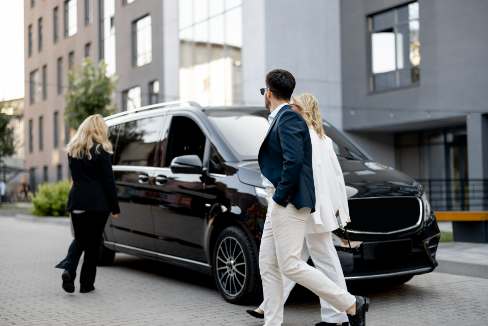 Van premium noir avec couple et hôtesse à l'arrivée
